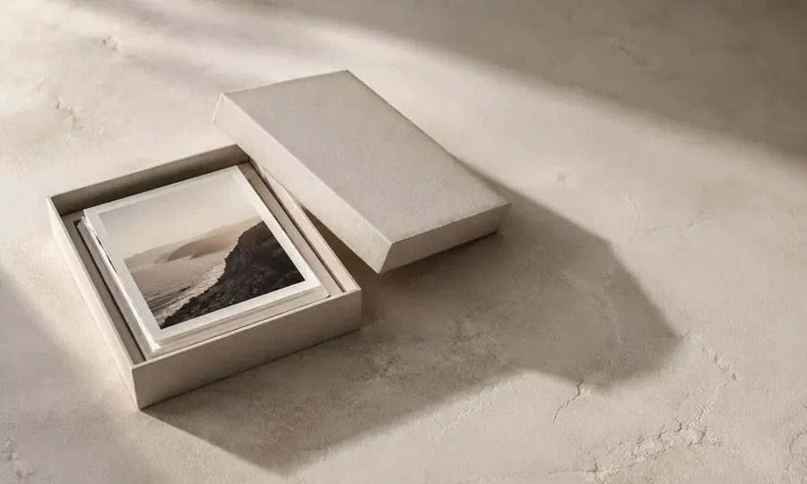 Open archival photo box with prints inside on a bare plaster surface